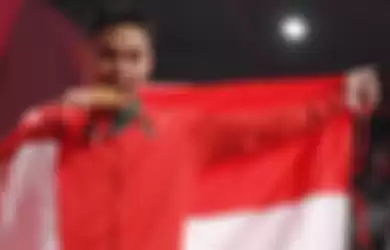 Lifter Indonesia Eko Yuli menggigit medali emasnya usai menjuarai angkat besi putra grup A nomor 62 