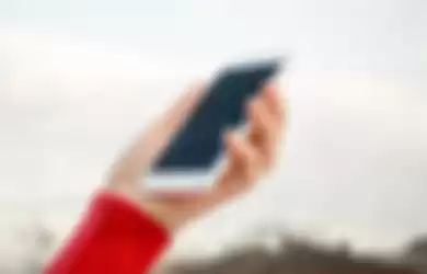 hand holding a wet smartphone under rain