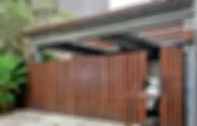 <p>Pagar carport terbuat dari kayu merbau. Warna cokelat khas kayu melembutkan area carport yang kaku karena warna abu-abu acian semen.Susunan kayu pada pagar dibuat vertikal.</p>