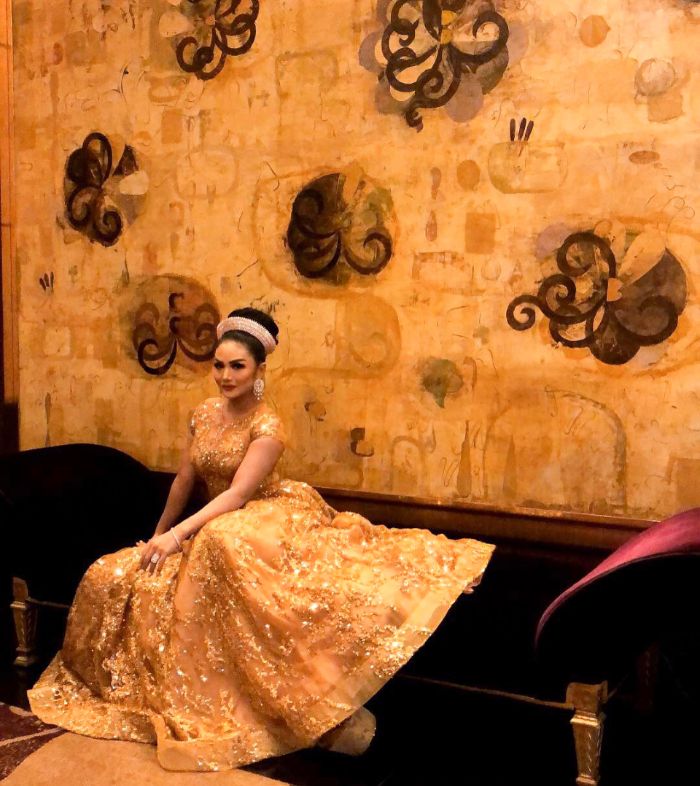 Krisdayanti mengenakan gaun dengan nuansa warna emas atau gold
