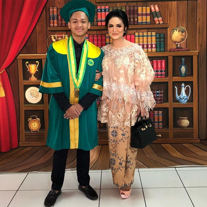 Krisdayanti mengenakan blouse berhiaskan lace dengan detail lengan drop puffed