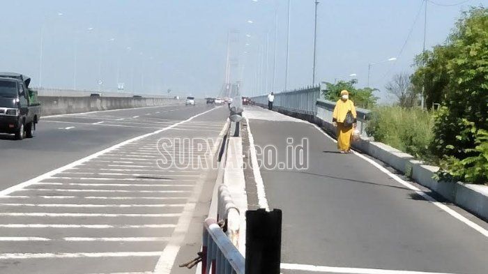 Seorang wanita bergamsi kuning tampak berjalan kaki di Jembatan Suramadu