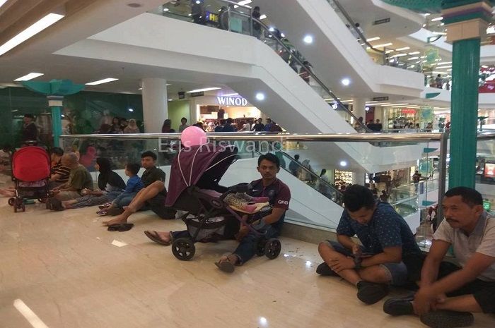 Para pria terduduk di lantai mall untuk menunggu istrinya belanja