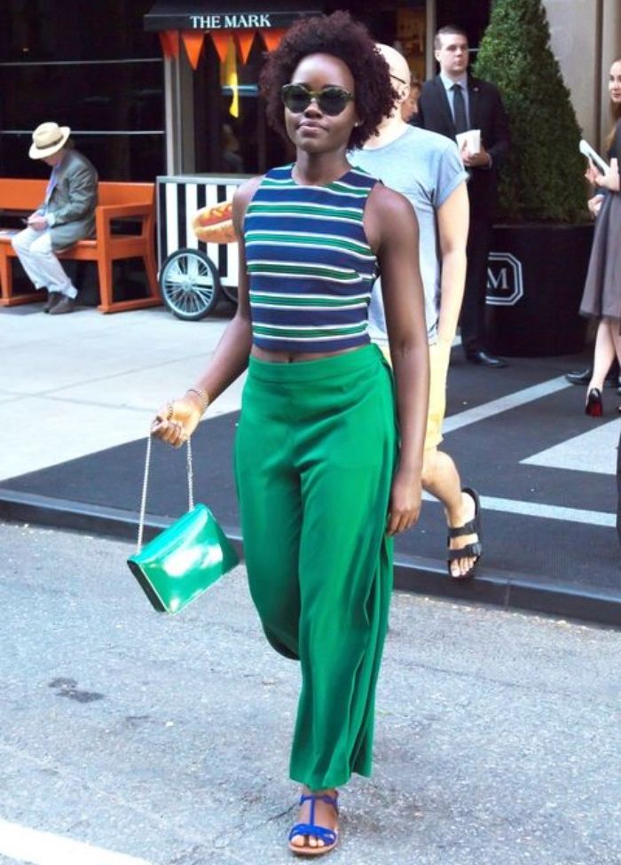 Lupita Nyong’o memadukan crop top bermotif stripe dengan celana palazzo.