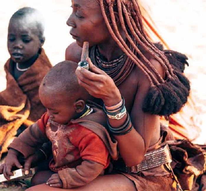 Wanita suku Himba mengolesi tubuhnya dengan oker.