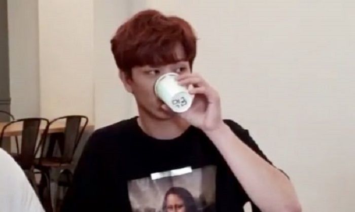 Yook Sungjae mengangkat gelas kertas untuk menunjukkan kata meok-geum