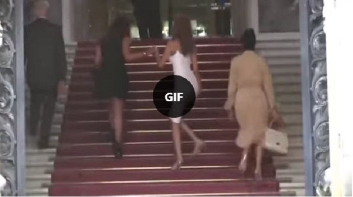 Perempuan yang menggunakan busana ketat ini akhirnya dibantu oleh seorang perempuan untuk menaiki tangga.