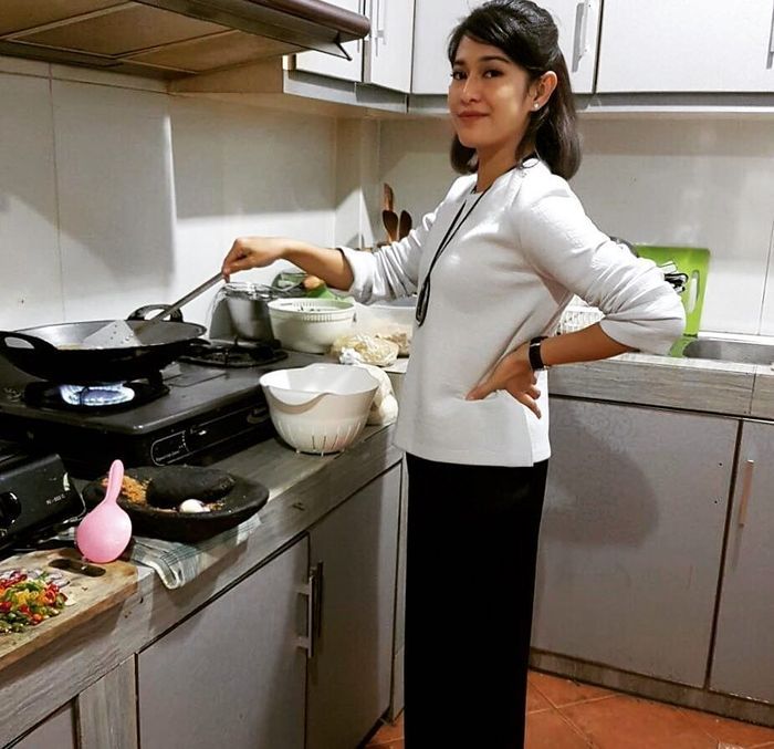 Dian Sastro sedang memasak di dapur