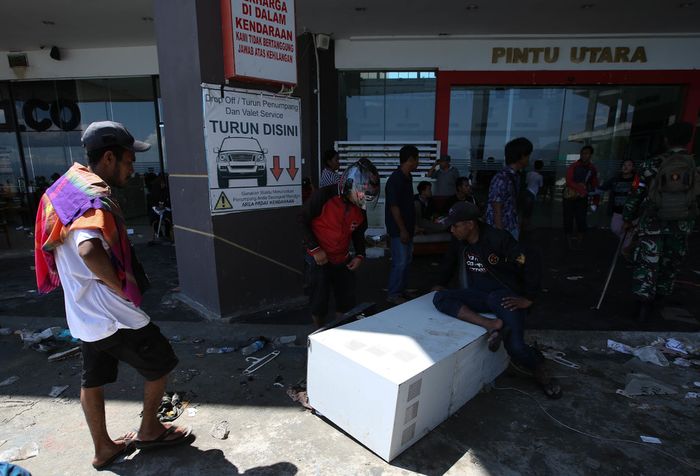 Warga menjarah barang di Grand Palu Mall usai gempa bumi di Pura, Kota Palu, Sulawesi Tengah, Minggu (30/9/2018). Gempa bermagnitudo 7,4 yang mengguncang Donggala dan Palu mengakibatkan ribuan bangunan rusak dan sedikitnya 420 orang meninggal dunia.