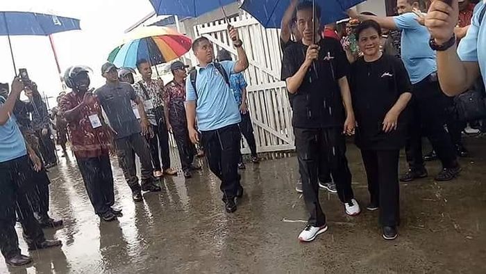 Jokowi memayungi Iriana
 