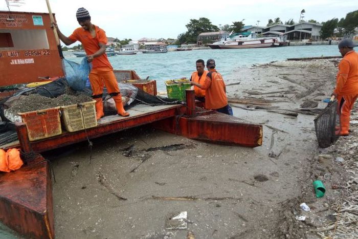 Petugas kebersihan membersihkan kerikil di Kepulauan Seribu