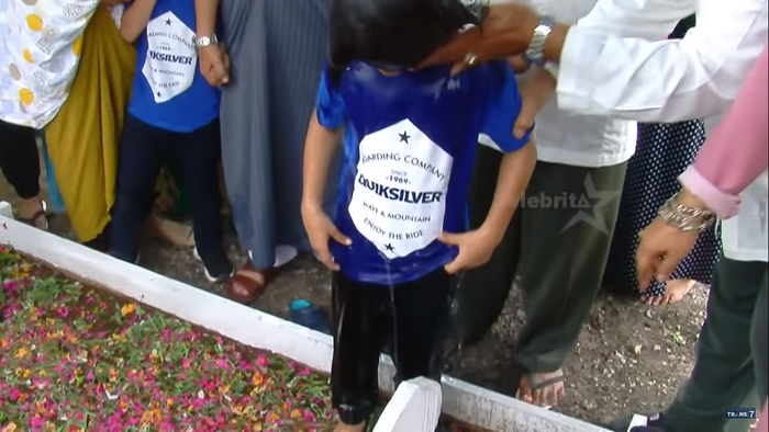 Fuza dimandikan di atas makam sang ayah.