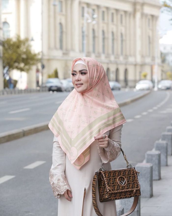 Dalam foto ini ia menggunakan gamis berwarna beige yang dipadukan dengan hijab motif berwarna peach yang serasi.