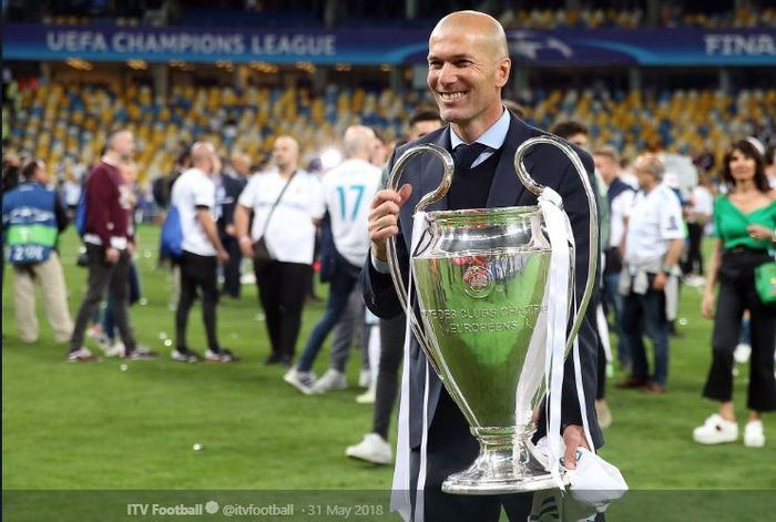 Pelatih Real Madrid, Zinedine Zidane, memegangi trofi juara Liga Champions.