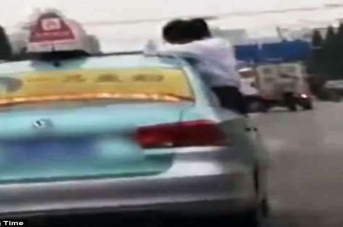 Sang remaja bisa menyeimbangkan tubuhnya di jendela taksi yang sempit