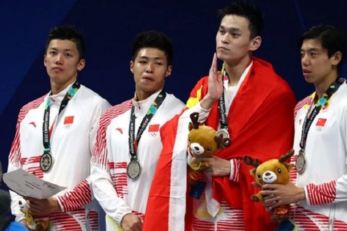 Sun Yang berselubung bendera saat terima medali sementara rekan-rekannya mengenakan jaket