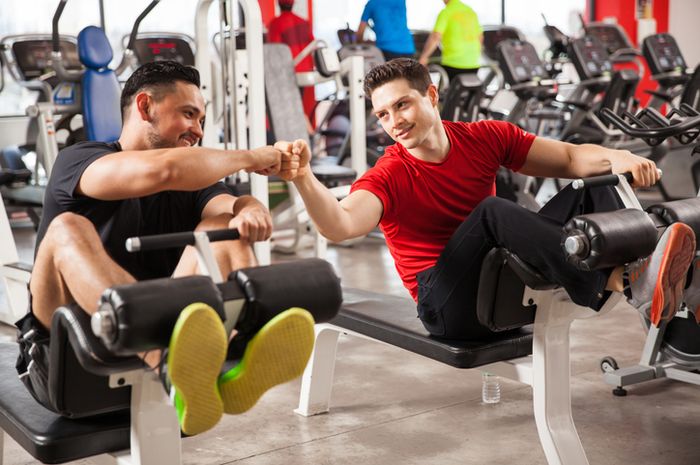 Two athletic young man bumping their fists as a sign of friendship and working out together at a gym