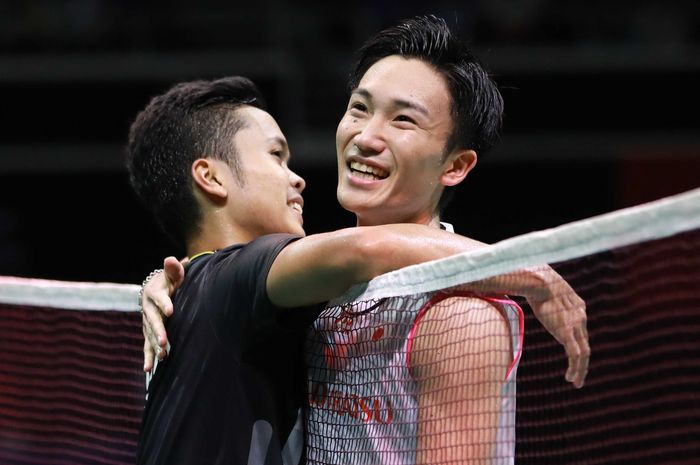 Pebulu tangkis tunggal putra Indonesia, Anthony Sinisuka Ginting, merangkul Kento Momota (Jepang) seusai laga final Singapore Open 2019 di Singapore Indoor Stadium, Minggu (14/4).