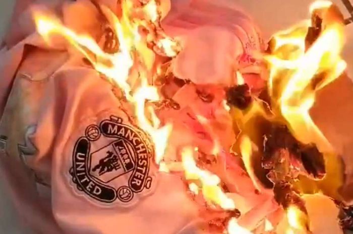 Suporter Manchester United membakar jersey klub.