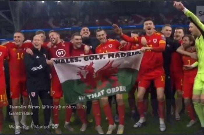 Pemain sayap timnas Wales, Gareth Bale, membawa bendera sindiran untuk klubnya, Real Madrid, saat merayakan kelolosan ke Piala Eropa 2020.