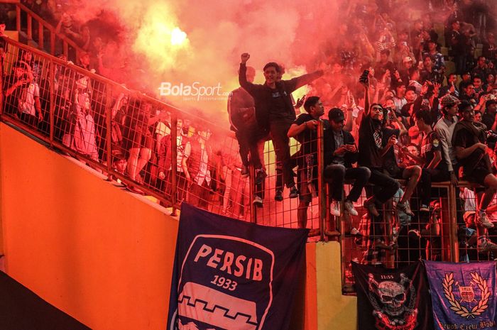Suporter Persib Bandung (pendukung Persib Bandung) sedang menyalakan flare atau kembang api atau suar atau petasan seusai laga di Stadion Wibawa Mukti, Cikarang, Jawa Barat, 24 Juli 2022.
