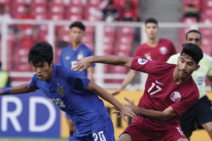 Pemain tengah timnas U-19 Thailand, Airfan Doloh (kiri) berebut bola dengan pemain timnas U-19 Qatar