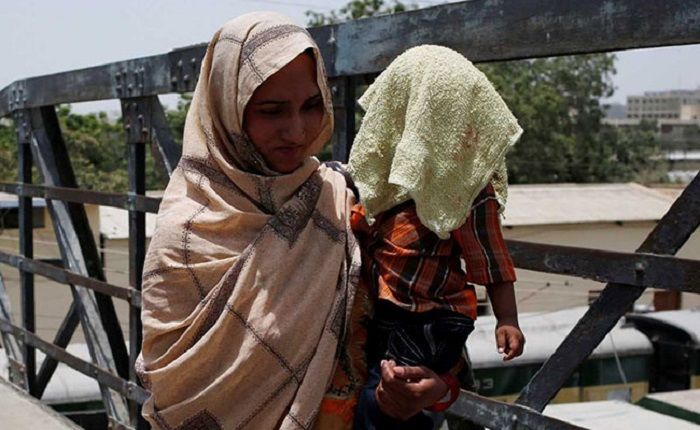 Seorang ibu memegang anaknya saat gelombang panas di Karachi, Pakistan