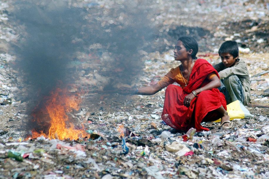 Ibu dan anak membakar sampah di dekat pemukiman kumuh Hyderabad, India.