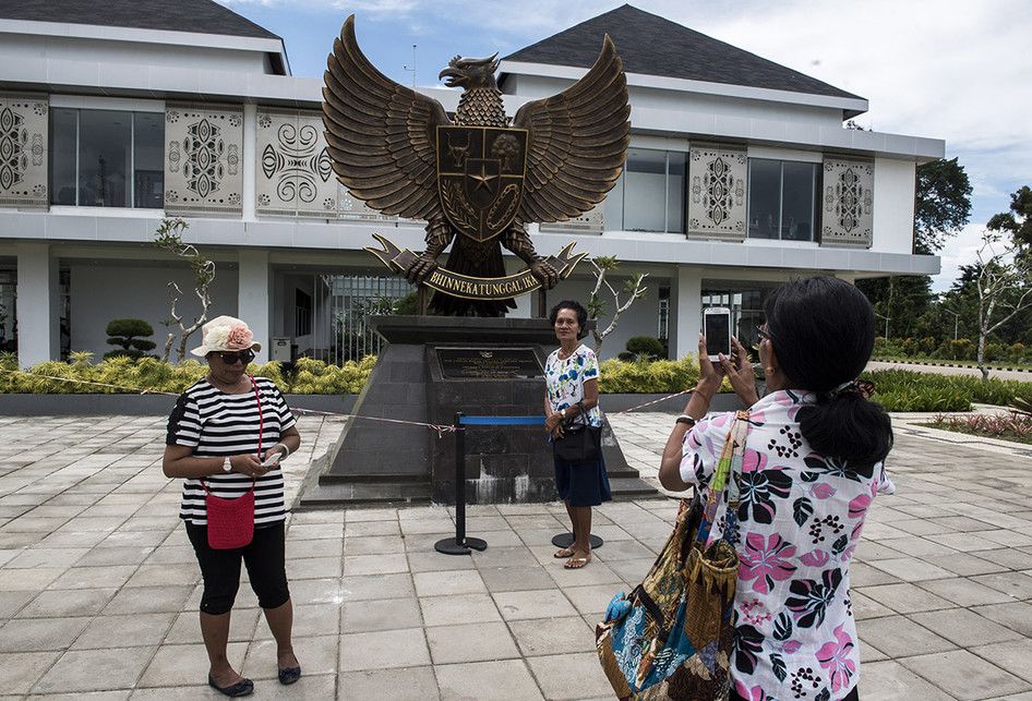 Pengunjung berfoto di depan tugu Garuda Indonesia di Pos Lintas Batas Negara (PLBN) Terpadu Skouw di