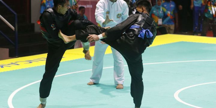 ￼ Pesilat Indonesia Komang Harik Adi Putra (sabuk merah) melakukan serangan kepada pesilat Malaysia Mohd Al Jufferi Jamari dalam babak final Kelas E Putra Asian Games 2018 di Padepokan Pencak Silat Taman Mini Indonesia Indah (TMII), Jakarta, Senin (27/8/2018). Komang berhasil meraih medali emas cabang olahraga pencak silat kelas 65-70 kilogram. 