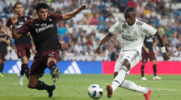 Real Madrid's Vinicius Junior (R) vies for the ball with Milan's Raoul Bellanova during the Santiago