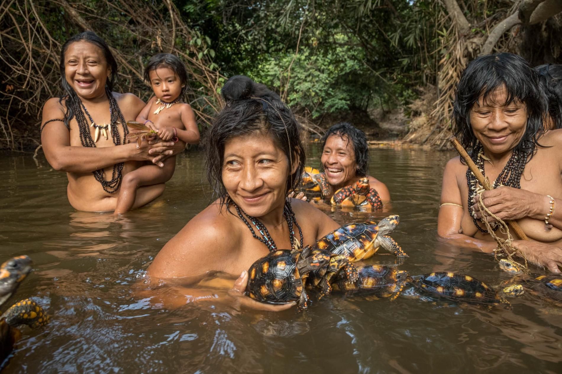 Para wanita suku Awa mandi di aliran sungai.
