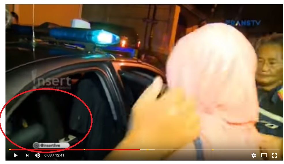 terlihat seorang pria telah berada di dalam mobil polisi (lingkaran merah)