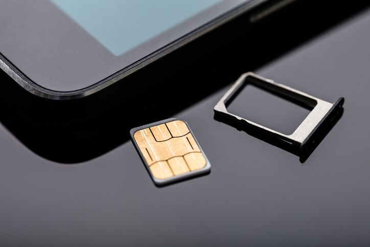 Close-up Of Nano Sim Card Ready To Insert In Smart Phone Over The Desk