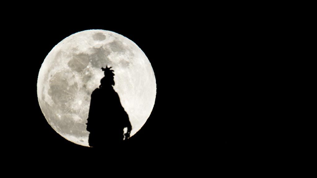 Siluet patung kebebasan yang berada di puncak kubah US Capitol di Washington DC, dengan latar belakang gerhana bulan istimewa. 
