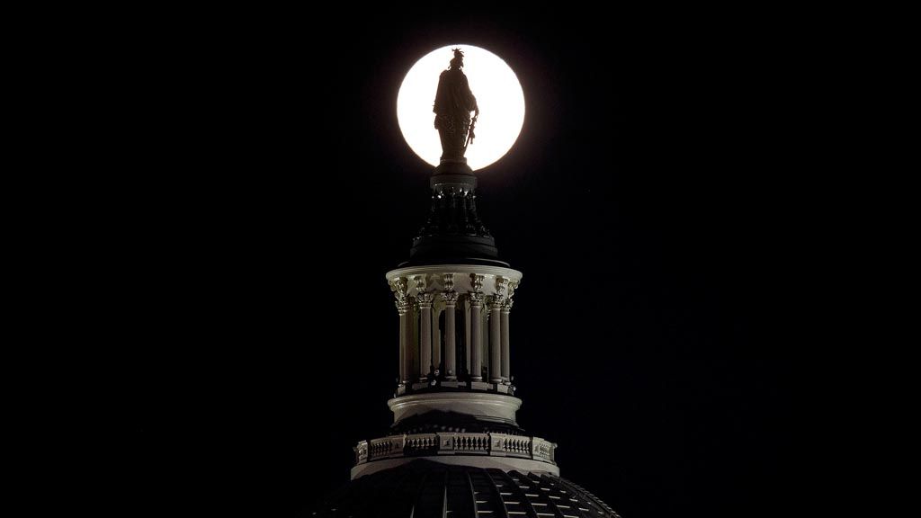 Siluet patung kebebasan yang berada di puncak kubah US Capitol di Washington DC, dengan latar belakang gerhana bulan istimewa Super blood Wolf Moon, Minggu (20/1/2019).