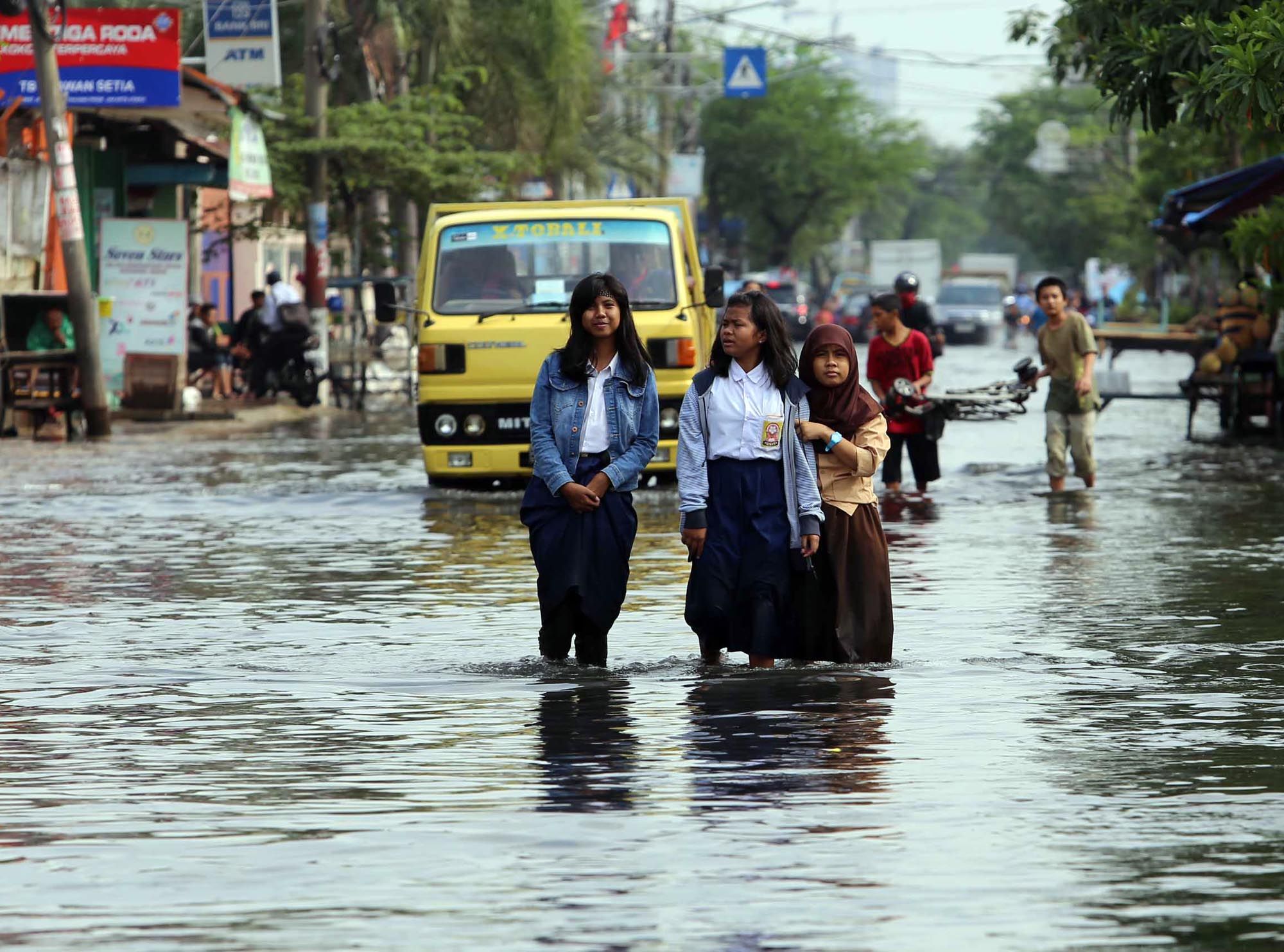 Siswa sekolah melintasi banjir yang menggenangi Jalan Kramat Jaya, Semper Barat, Jakarta Utara, Rabu (12/3/2014). Setiap kali hujan lebat mengguyur kawasan itu, jalan tersebut selalu banjir. Hal itu diperparah oleh sistem drainase yang buruk. Warta Kota/angga bhagya nugraha