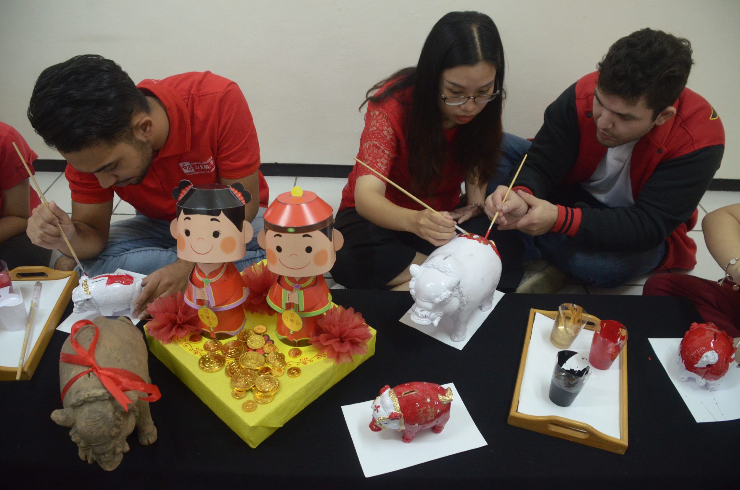 KENALKAN BUDAYA IMLEK - Mahasiswa Universitas Surabaya (Ubaya) berkolaborasi buat kreasi hias babi dari celengan babi berbahan tanah liat bersama mahasiswa asing dari Vietnam, Tajikistan dan Kanada yang mengikuti program Darmasiswa Republik lndonesia di  Gedung International Village Ubaya, Selasa (2