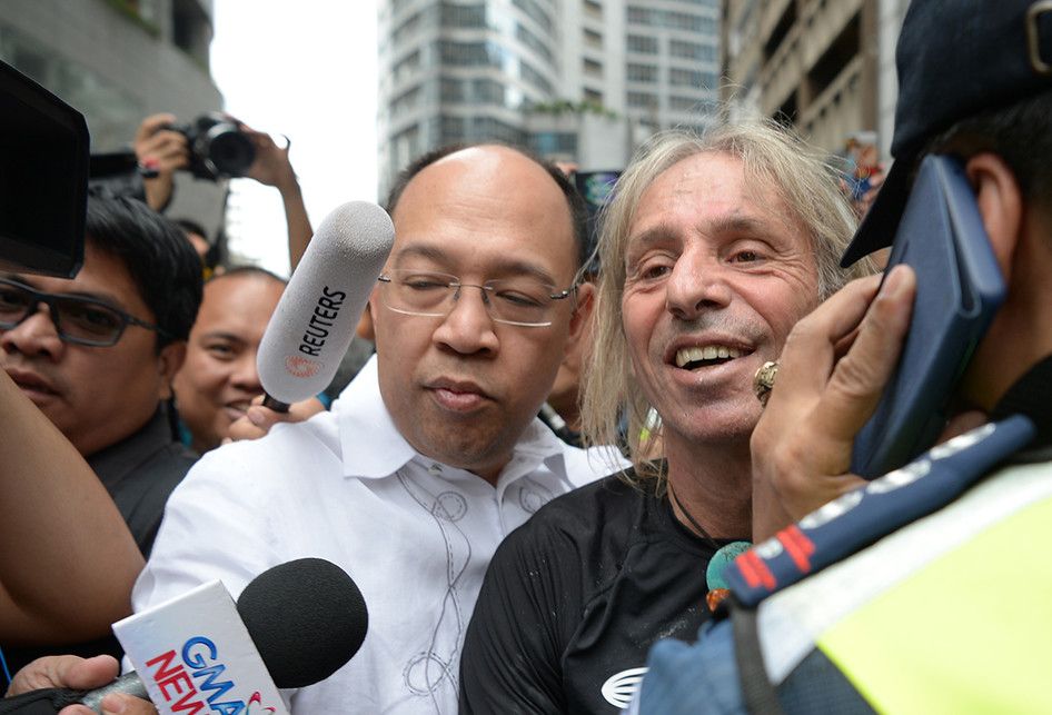 Pemanjat gedung asal Perancis, Alain Robert, didampingi pengacaranya, Howard Calleja (kemeja putih) saat diarahkan ke dalam mobil polisi usai ditangkap karena aksinya memanjat sisi GT Tower di Makati, Filipina, Selasa (29/1/2019). Pria dengan julukan 'Spider-Man' berusia 56 tahun itu kemudian ditang