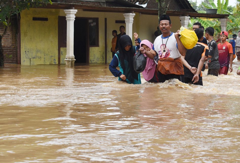 Warga melintasi jalan yang terendam banjir di Desa Kedungrejo, Pilangkenceng, Kabupaten Madiun,  Jawa Timur, Rabu (6/3/2019). Sejumlah anak Sungai Madiun meluap dan merendam sejumlah desa di wilayah tersebut, sehingga ratusan warga yang terjebak banjir harus dievakuasi ke tempat yang lebih aman.