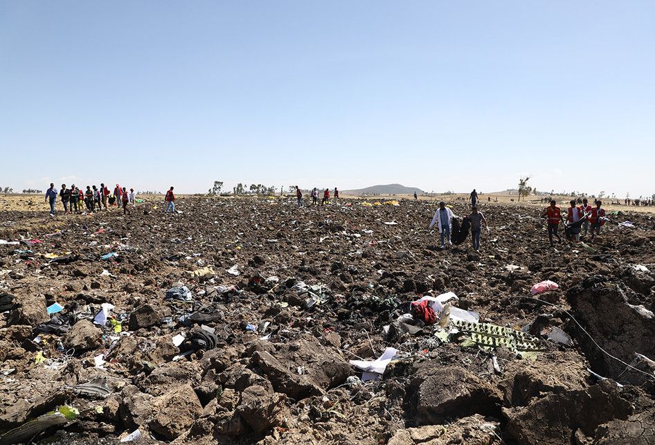 Petugas mengevakuasi jenazah di lokasi jatuhnya pesawat Ethiopia Airlines di kawasan Bishoftu, sebuah kota sekitar 60 kilometer tenggara Addis Ababa, Ethiopia, Minggu (10/3/2019). Sebanyak 157 orang terdiri dari penumpang dan kru pesawat Ethiopian Airlines dipastikan tewas setelah Boeing 737-8 MAX y