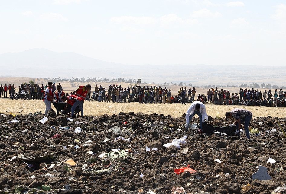 Petugas mengevakuasi jenazah di lokasi jatuhnya pesawat Ethiopia Airlines di kawasan Bishoftu, sebuah kota sekitar 60 kilometer tenggara Addis Ababa, Ethiopia, Minggu (10/3/2019). Sebanyak 157 orang terdiri dari penumpang dan kru pesawat Ethiopian Airlines dipastikan tewas setelah Boeing 737-8 MAX y