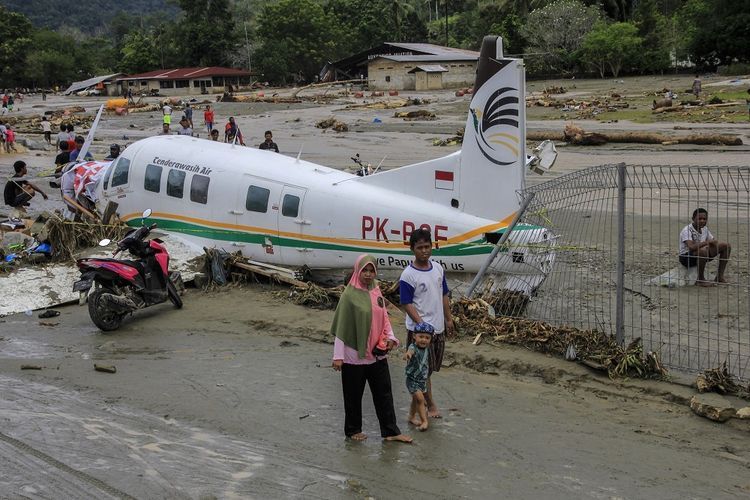 Warga berada di dekat pesawat udara yang terdampak banjir bandang di Sentani, Kabupaten Jayapura, Papua, Minggu (17/3/2019). Berdasarkan data BNPB, banjir bandang yang terjadi pada Sabtu (16/3/2019) tersebut mengakibatkan 63 orang meninggal dunia. 