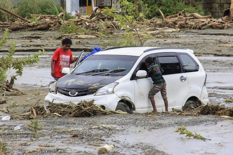 Kendaraan terendam lumpur saat banjir bandang di Sentani, Kabupaten Jayapura, Papua, Minggu (17/3/2019). 