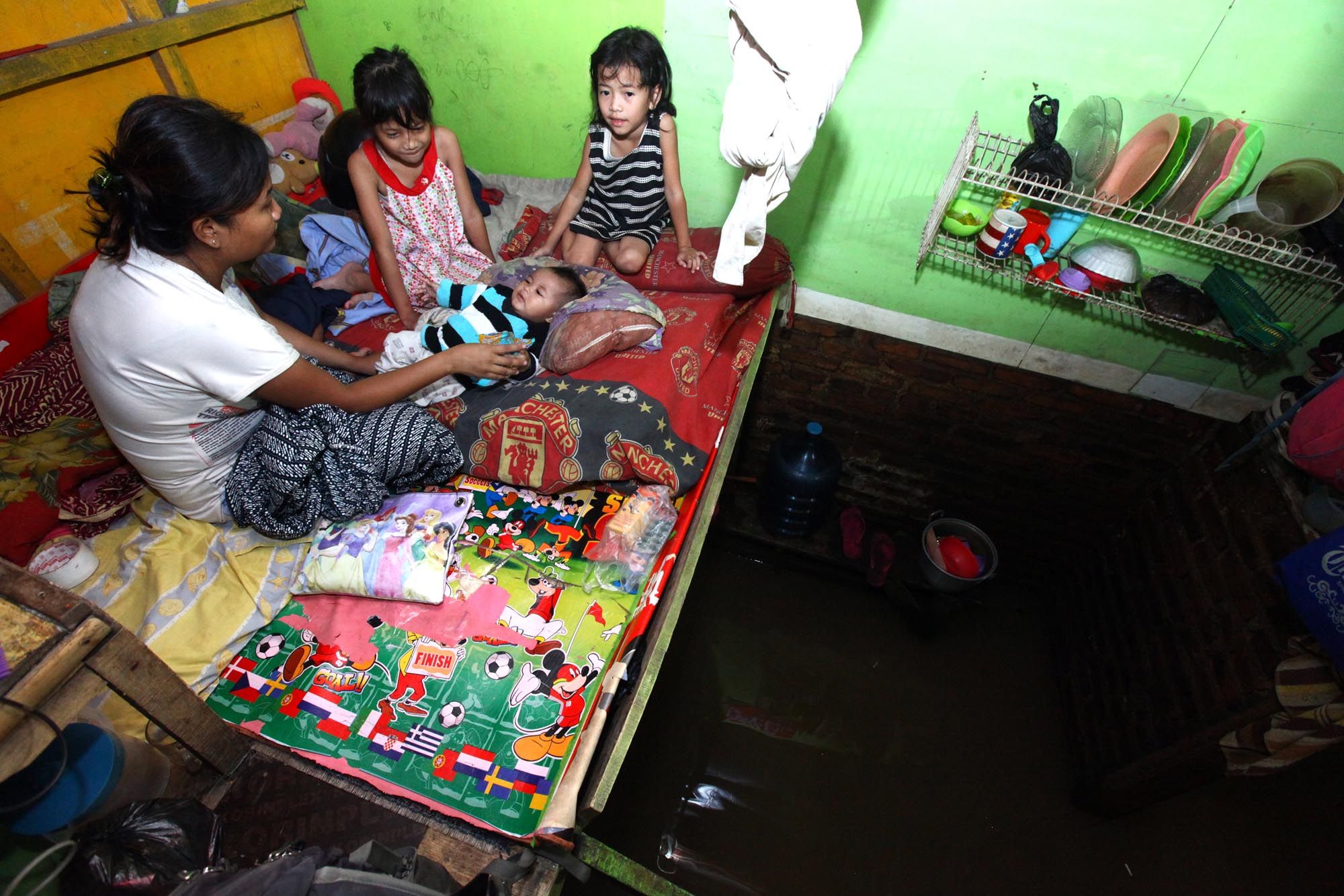 Dewi Komalasari (25) bersama bayi dan dua anaknya bermain di atas panggung di kamarnya yang terendam banjir di Kampung Jambatan, Kelurahan Andir, Kecamatan Baleendah, Kabupaten Bandung, Rabu (27/3/2019). Pemukiman warga di Kelurahan Andir ini sudah dua bulan terendam banjir, hingga memaksa sebagian 