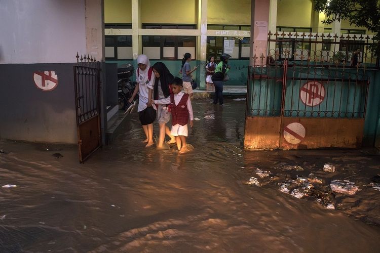 Warga melintasi genangan banjir bandang di SDN 224, Sukup Baru, Ujungberung, Bandung, Jawa Barat, Senin (1/4/2019). Banjir tersebut terjadi karena meluapnya Kali Cicalobak saat intensitas curah hujan yang tinggi yang merusak tanggul sehingga merendam sejumlah pemukiman warga serta merusak sebuah sebuah sekolah dasar