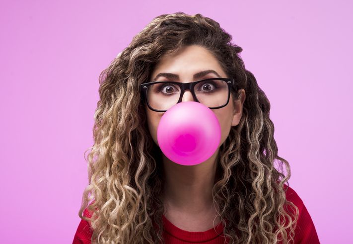 Beautiful young woman blowing a bubble gum balloon