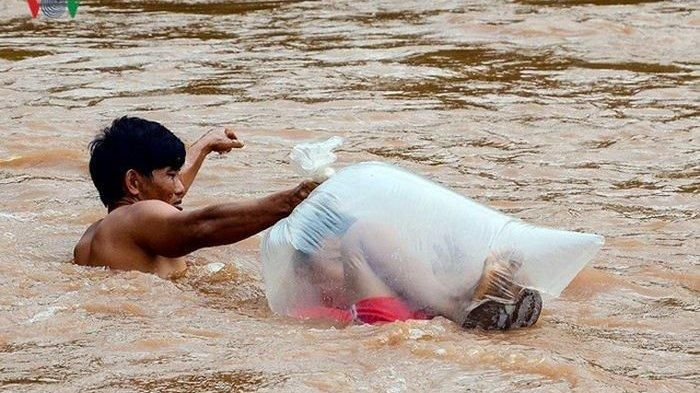 Anak-anak menyebrangi sekolah dengan dimasukkan ke dalam kantong plastik