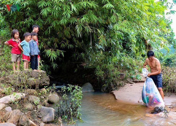 Anak-anak dimasukkan kantong plastik sebelum menyebrangi sungai