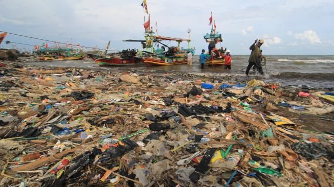 Nelayan menyandarkan perahunya di bibir pantai yang dipenuhi sampah plastik di Desa Dadap, Indramayu, Jawa Barat, Senin (26/11). ANTARA FOTO/Dedhez Anggara